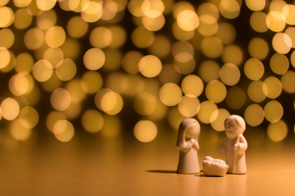 Small nativity scene in front of fairy lights.